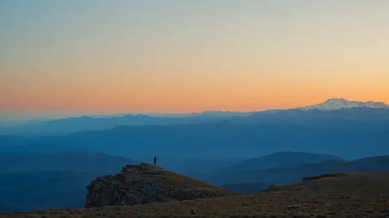 Una silueta contempla el amanecer entre montañas